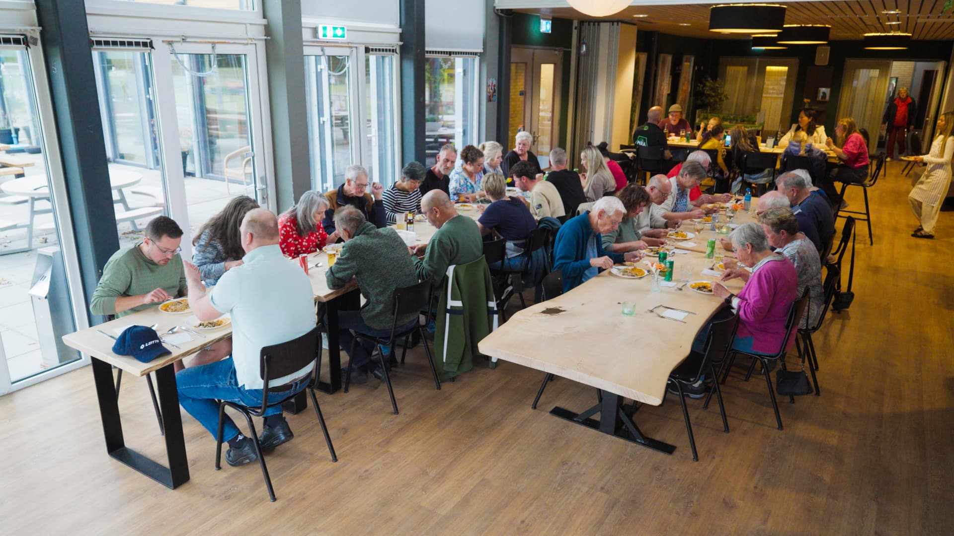Dorpsgenoten eten samen aan lange tafels in De Gaveborg